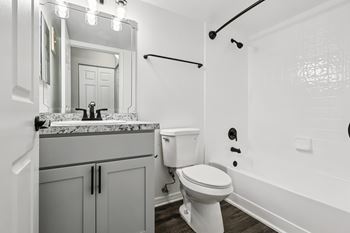 A white toilet in a bathroom with a marble countertop and a mirror above it.